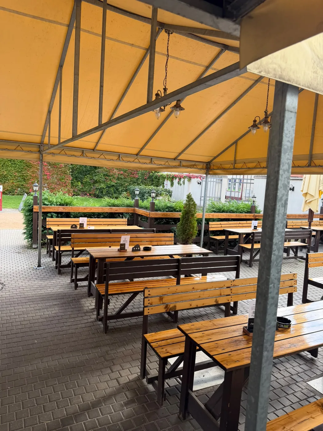 Krytá terasa s dřevěnými lavicemi a stoly